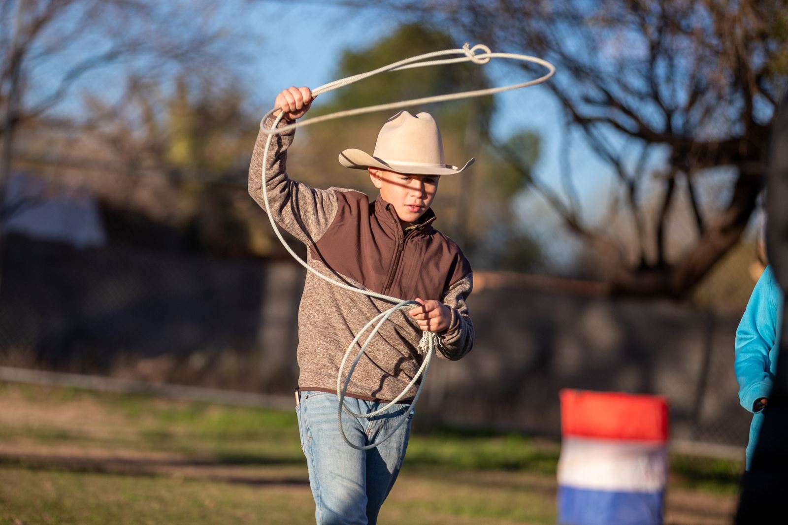 A boy in a cowboy hat practices his lassoing skills