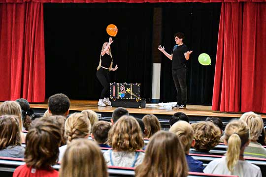 Students perform with balloons on stage.