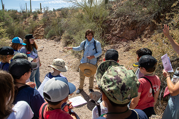 A man talks to students on a hike